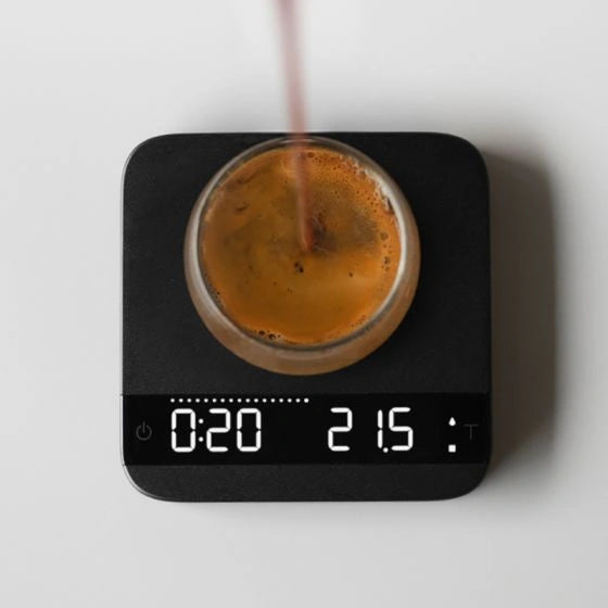Acaia Lunar Espresso Scale pouring espresso shot onto scale - Black coffee brewing scale showing '0:20' as time and '21.5' as grams, on white background with heavy shadows