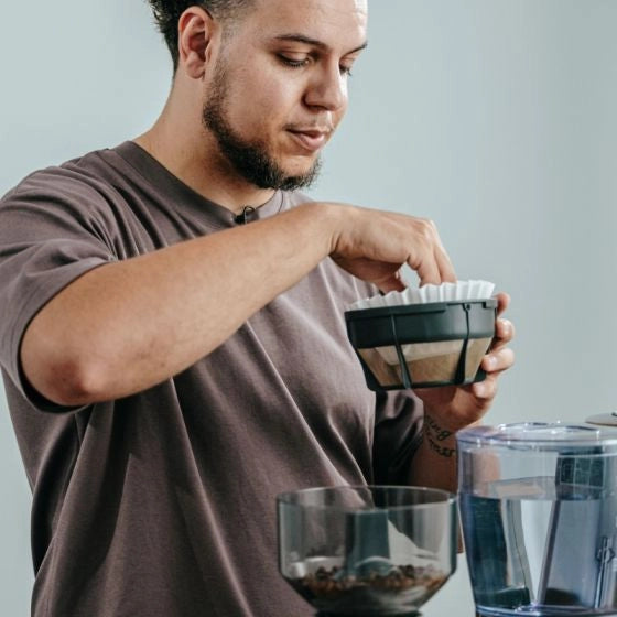 Jerome from Nucleus Coffee Tools preparing coffee using a grinder and a bowl on a light gray background - Bruer Spectrum Coffee Filters