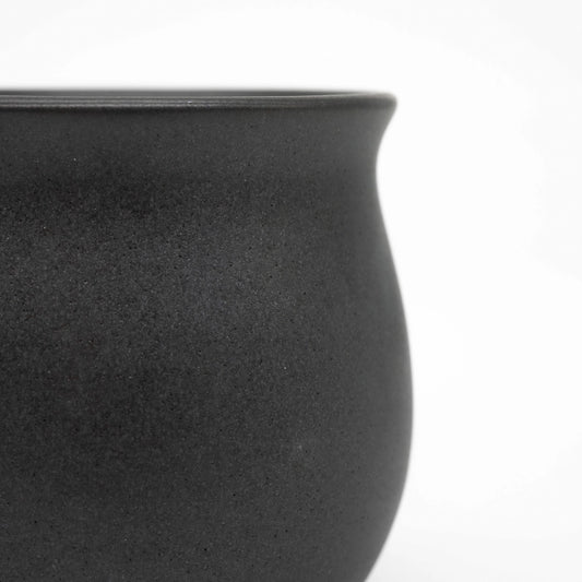 Close-up of a black ceramic origami pinot cup on a white background