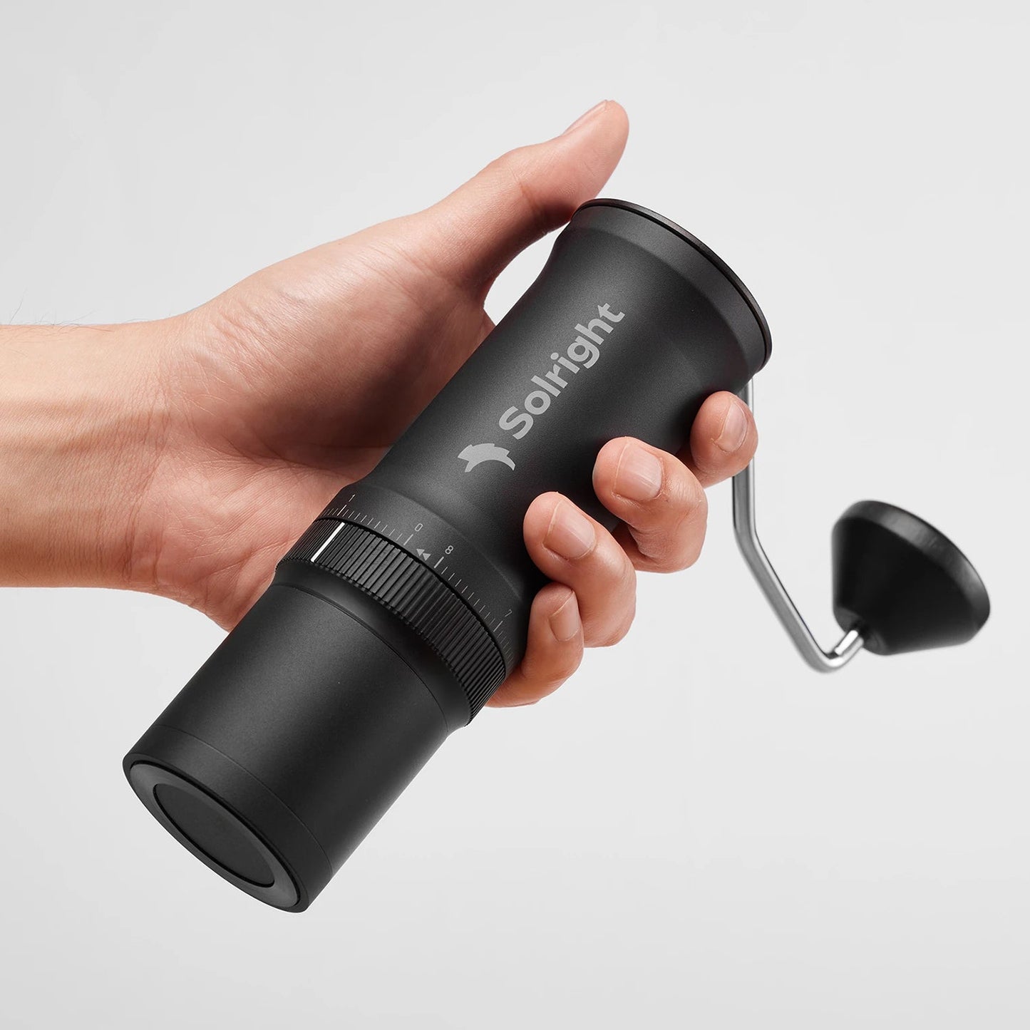 Hand holding a black portable coffee maker with 'Solright' branding on a light gray background Basic Barista Solright Grinder