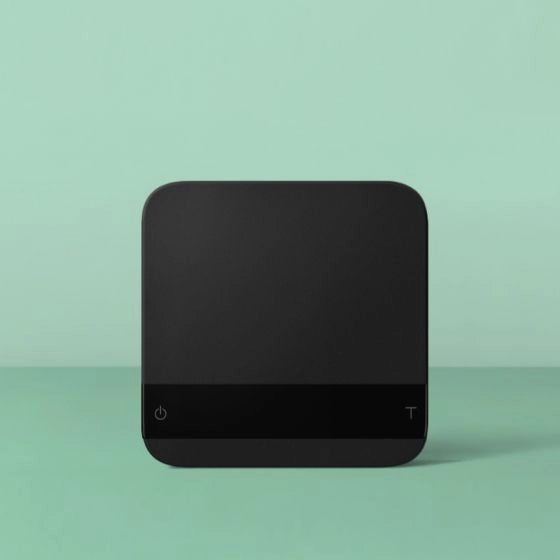 Black square Acaia Lunar Espresso scales with 'power' symbol button and 'tare' button on a light green background