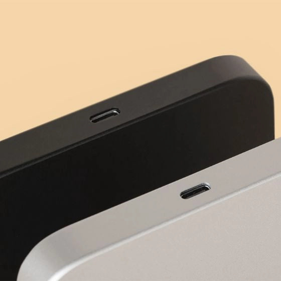 Close-up of a black and gray charging port on the Acaia Lunar Espresso scale on a beige yellow background