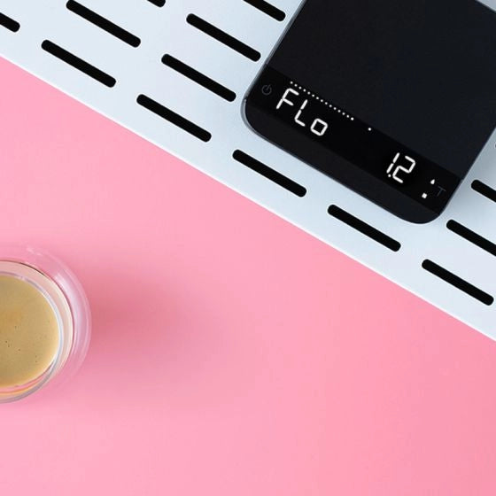 Digital Acaia Lunar Espresso scale with 'Flo' mode on a pink background with espresso in a glass