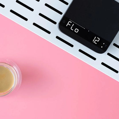 Digital Acaia Lunar Espresso scale with 'Flo' mode on a pink background with espresso in a glass