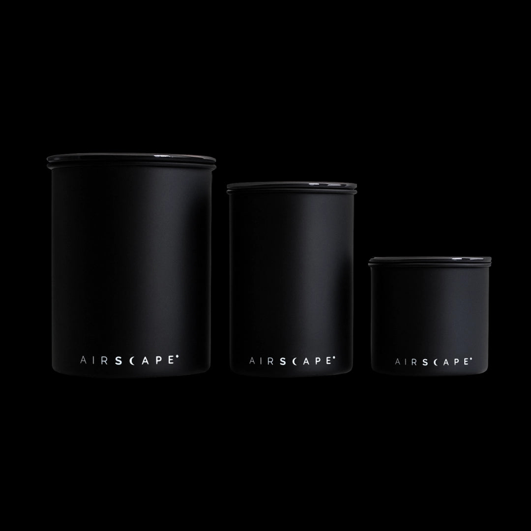 Three black air tight containers labeled 'AIRSCAPE' on a black background basic barista coffee gear