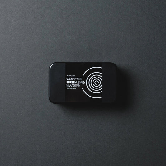 Black 'Aquacode' Tin of water brewing mineral sachets (liquid form) resting on black paper background with dark shadows - Basic Barista Product Image