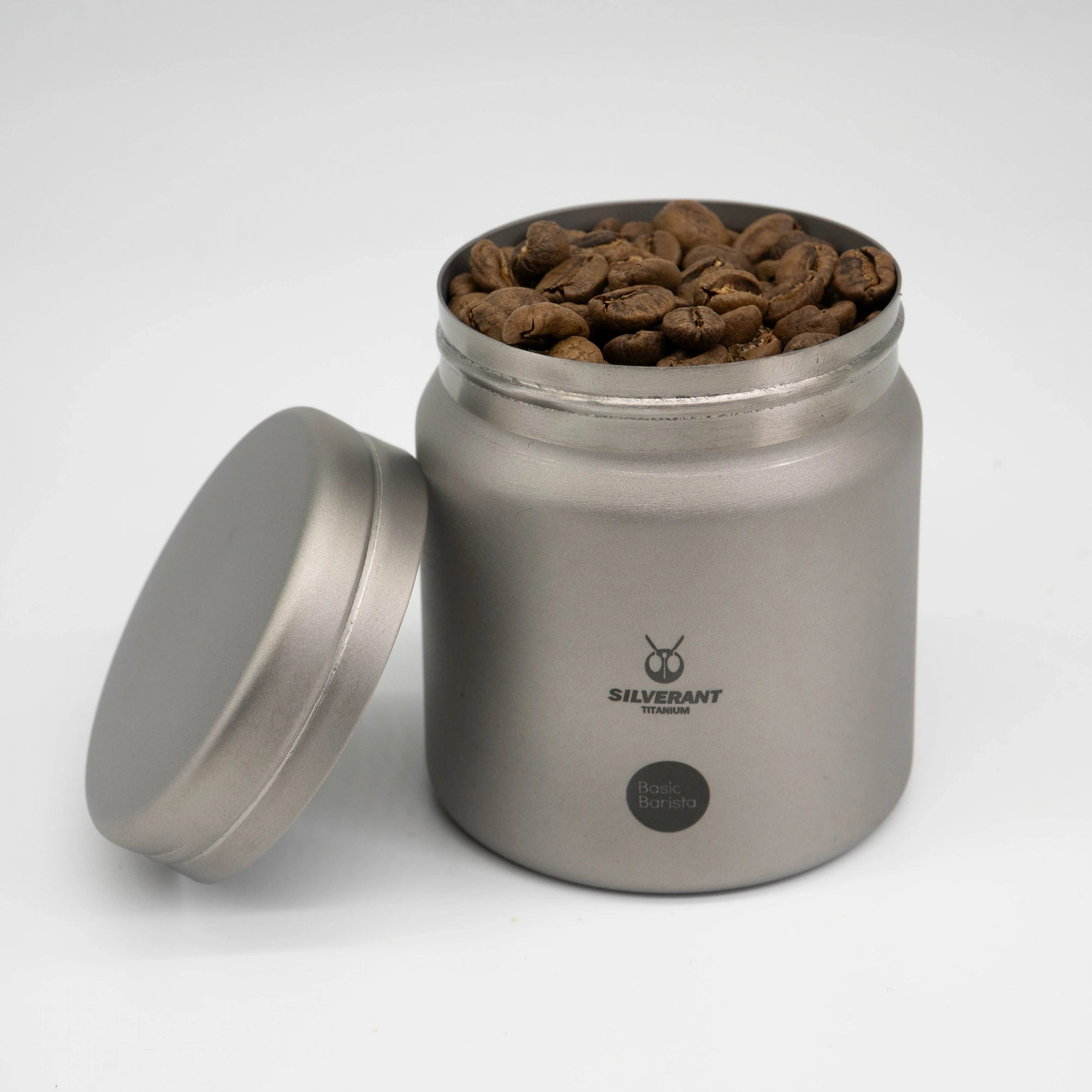 Silver titanium metal container with coffee beans on a white background Basic Barista Coffee Gear Logo Etched Coffee Bean Storage container