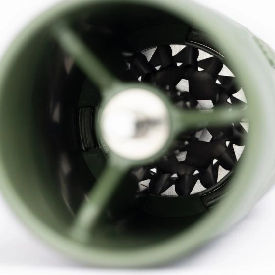 Close-up of a green travel coffee grinder with a black interior on a white background