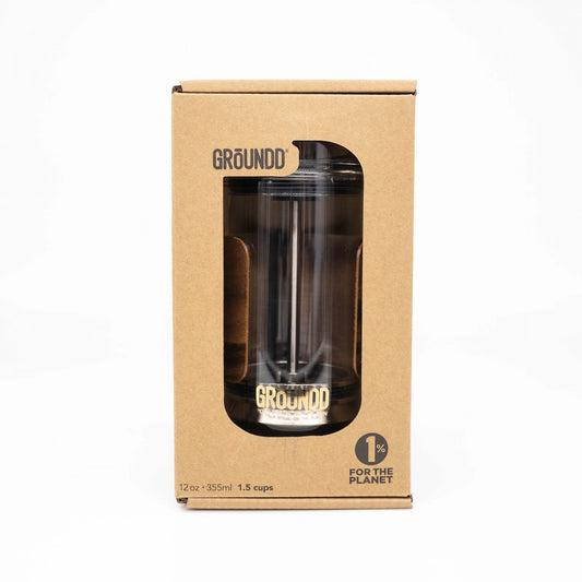 Groundd tumbler coffee press in its original brown cardboard packaging, featuring a clear window that displays the black glass tumbler with gold lettering.