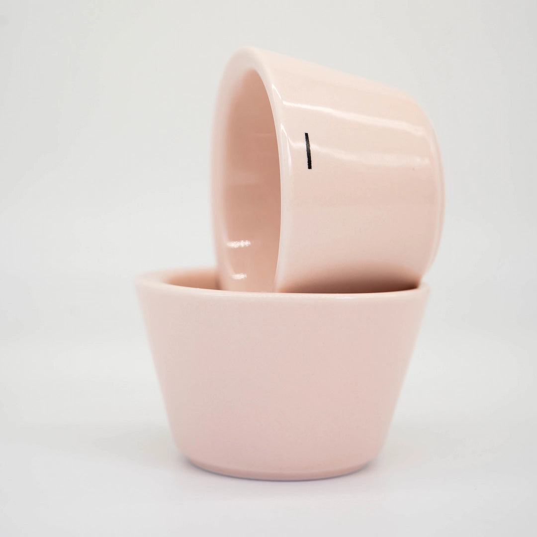 Two Pink Ni Wares Espresso Toto cups stacked on top of each other with one small '-' dash line symbolising the thin sided lip on a white background Basic Barista Cafe Equipment Espresso Coffee Cups