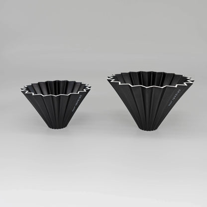 Two black pour over coffee drippers with white zigzag patterns flower dripper Origami coffee brewer on a white background