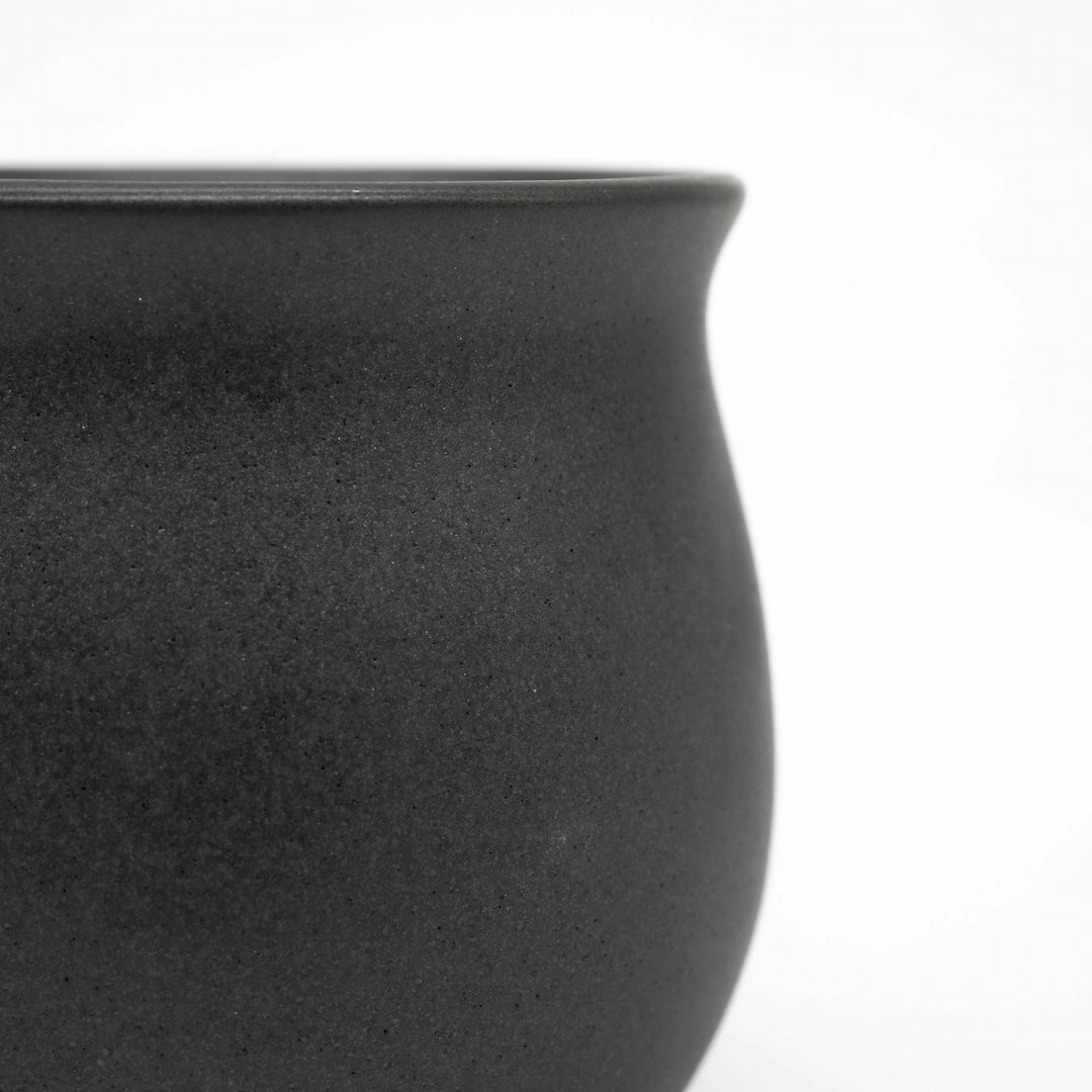 Close-up of a black ceramic origami pinot cup on a white background