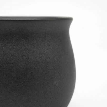 Close-up of a black ceramic origami pinot cup on a white background