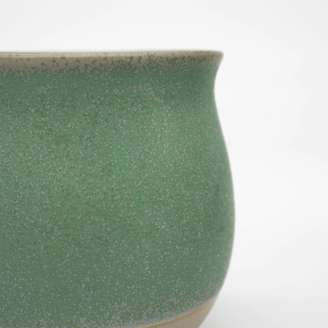Close-up of a green ceramic origami pinot cup on a white background