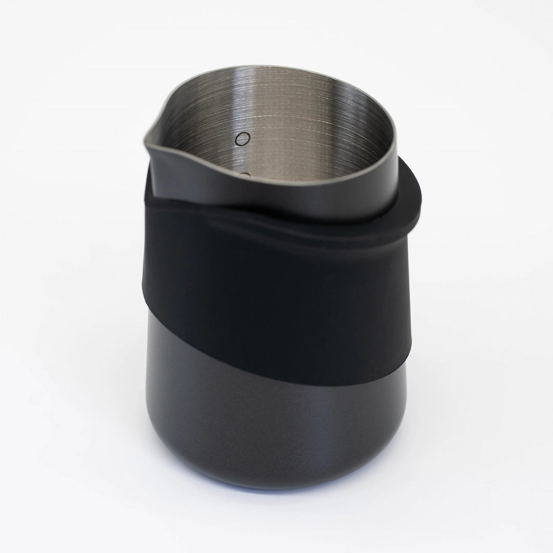 Subminimal Flow tip milk jug milk pitcher - handleless design with black silicone sleeve on a white background, close up of milk dot level markings - Basic Barista Coffee Gear Online