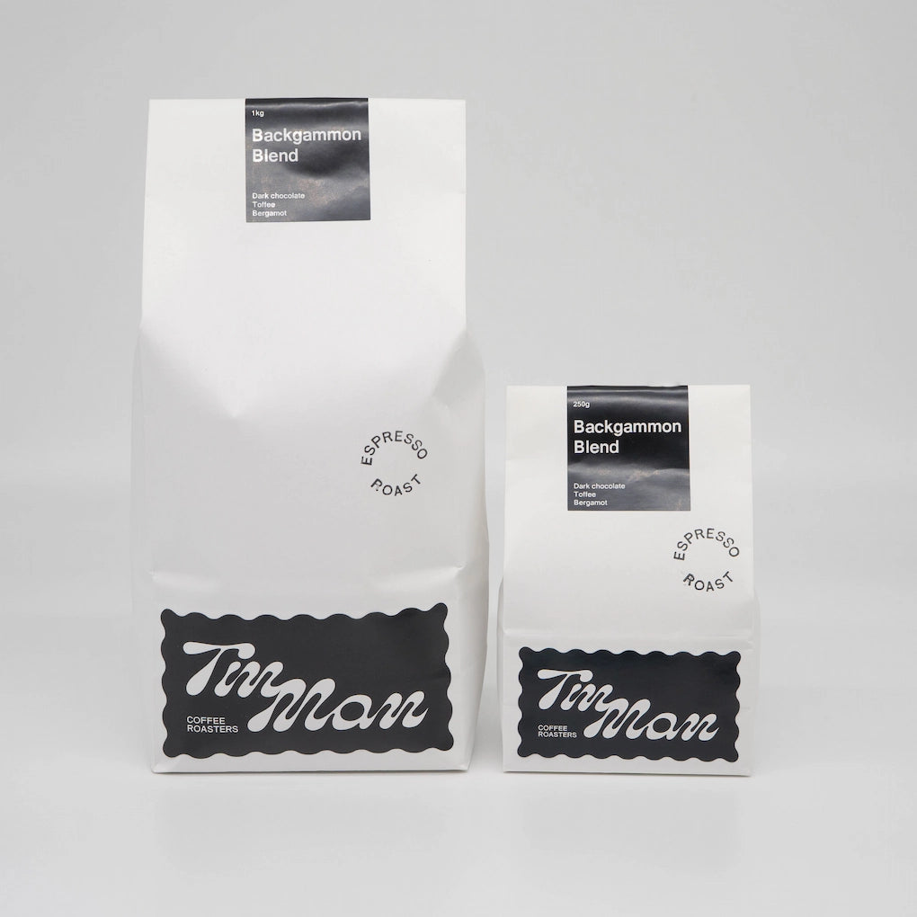 Two coffee bags labeled 'Tim Man Coffee Roasters' on a gray background Backgammon Blend Roasted Coffee Beans Basic Barista