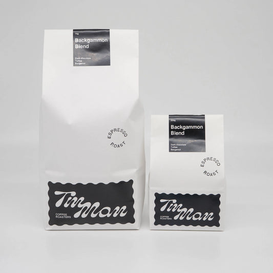 Two coffee bags labeled 'Tim Man Coffee Roasters' on a gray background Backgammon Blend Roasted Coffee Beans Basic Barista