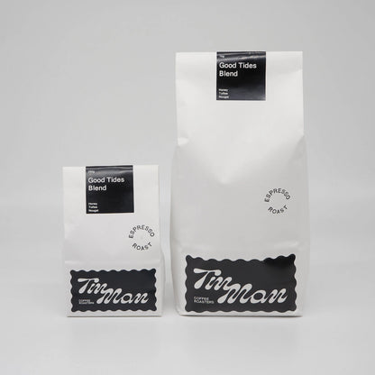 Two coffee bags labeled 'Good Tides Blend' by 'Tin Man' on a grey background Roasted Coffee Beans Basic Barista
