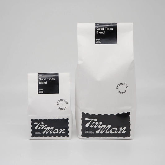 Two coffee bags labeled 'Good Tides Blend' by 'Tin Man' on a grey background Roasted Coffee Beans Basic Barista