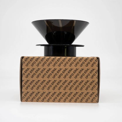Black plastic UFO Dripper sitting on top of retail box (Front view) on a white background Basic Barista Pour Over Coffee Gear